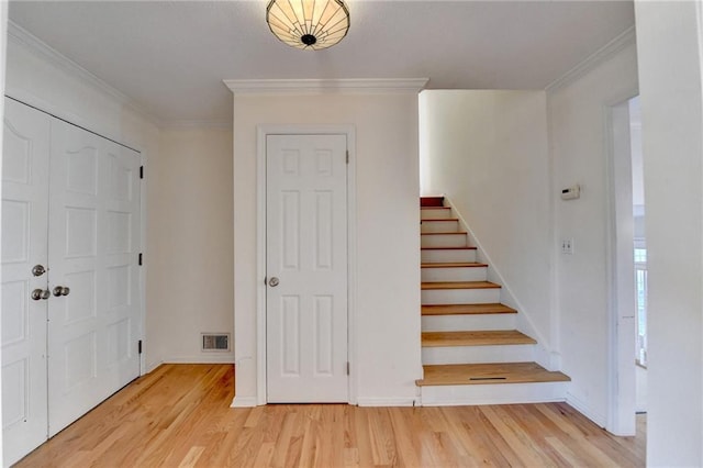 foyer entrance with ornamental molding and light hardwood / wood-style floors