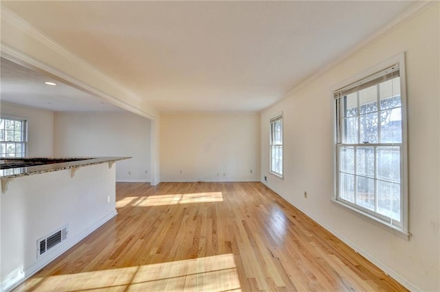 unfurnished living room featuring ornamental molding, a healthy amount of sunlight, and light wood-type flooring