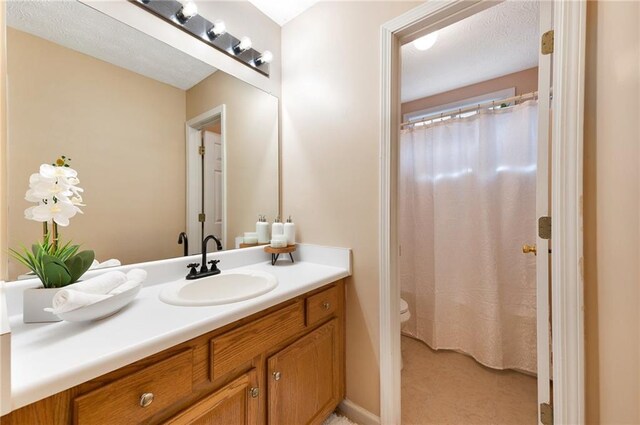 bathroom with a textured ceiling, vanity, and toilet