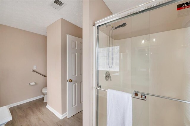 bathroom featuring hardwood / wood-style floors, toilet, and an enclosed shower