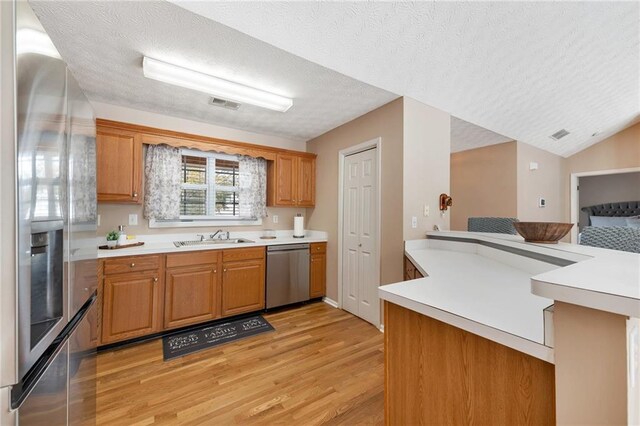 kitchen featuring sink, light hardwood / wood-style floors, a textured ceiling, and appliances with stainless steel finishes