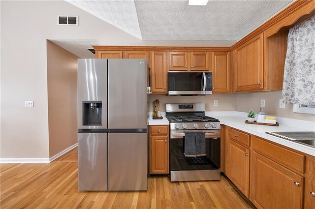 kitchen featuring sink, light wood-type flooring, a textured ceiling, and appliances with stainless steel finishes