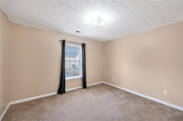 unfurnished room with light colored carpet and a textured ceiling