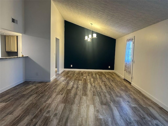 empty room with dark hardwood / wood-style flooring, lofted ceiling, a textured ceiling, and an inviting chandelier