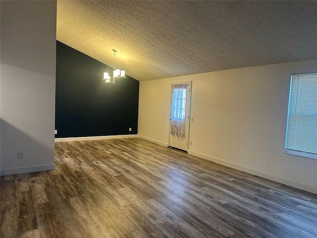 unfurnished room featuring a chandelier, wood-type flooring, a textured ceiling, and vaulted ceiling