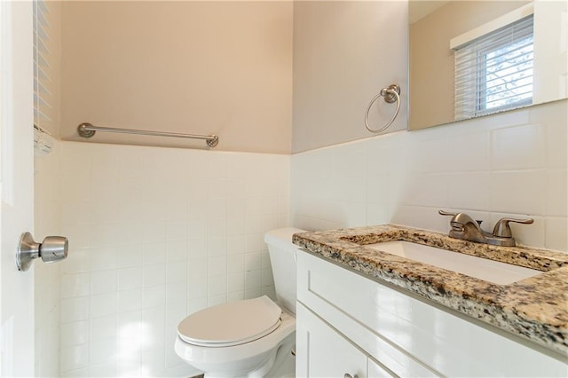 bathroom with vanity, toilet, and tile walls