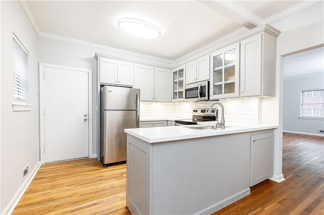 kitchen with stainless steel appliances, ornamental molding, sink, and white cabinets