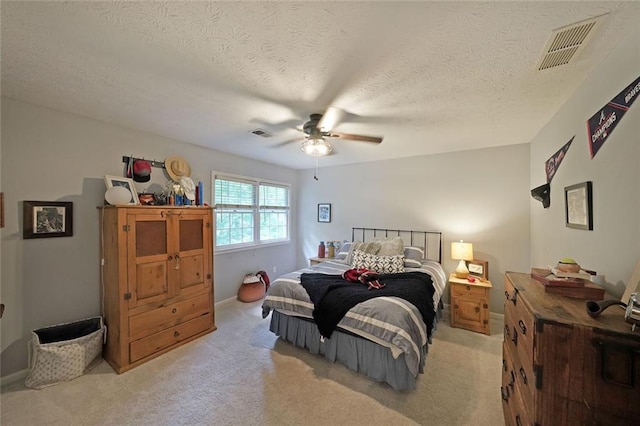 bedroom with visible vents, a ceiling fan, and light carpet