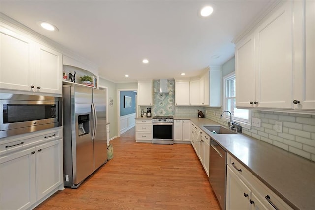 kitchen featuring wall chimney range hood, backsplash, a sink, white cabinets, and stainless steel appliances