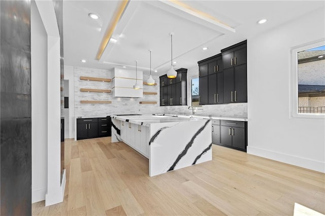 kitchen featuring open shelves, dark cabinetry, a kitchen island, and light countertops