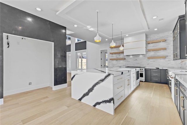 kitchen with decorative light fixtures, open shelves, custom range hood, white cabinetry, and light stone countertops