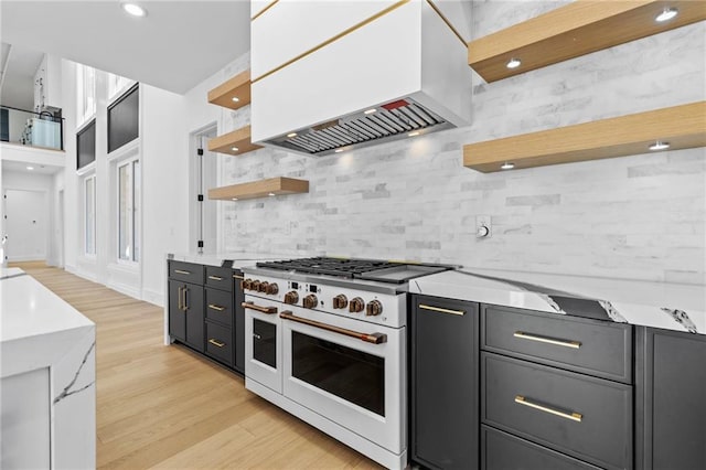 kitchen with island exhaust hood, light wood finished floors, open shelves, white cabinetry, and double oven range