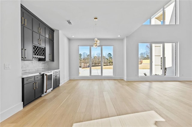 interior space featuring decorative light fixtures, visible vents, light countertops, beverage cooler, and dark cabinetry