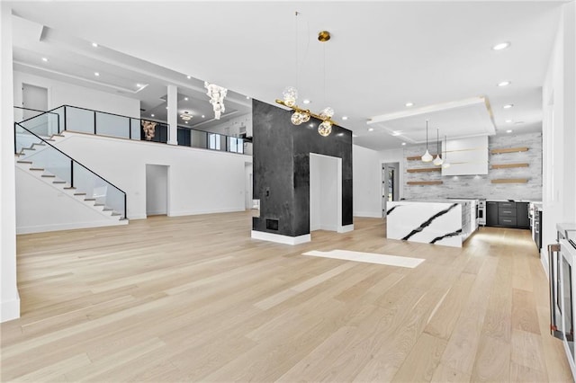 unfurnished living room with light wood-style floors, stairs, baseboards, and recessed lighting