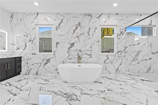 full bath with stone wall, a marble finish shower, a freestanding bath, and recessed lighting