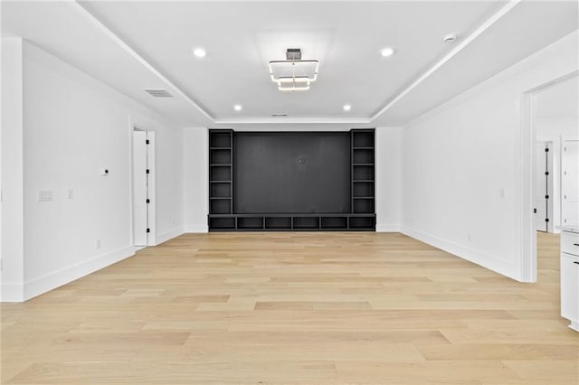 unfurnished room featuring visible vents, built in features, a raised ceiling, light wood-style floors, and recessed lighting