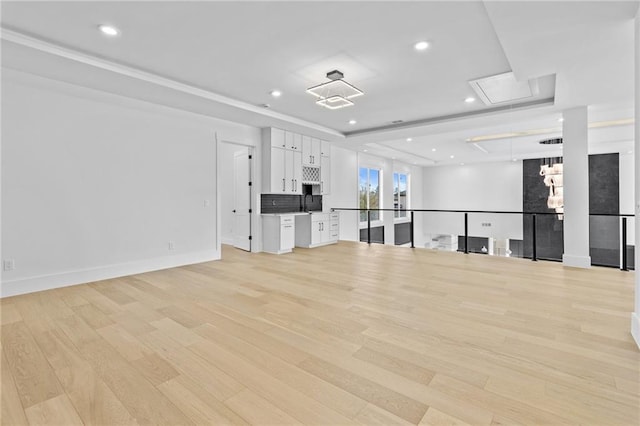 unfurnished living room featuring baseboards, light wood-type flooring, attic access, and recessed lighting