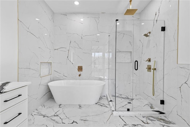 bathroom featuring marble finish floor, a marble finish shower, a freestanding bath, vanity, and stone wall