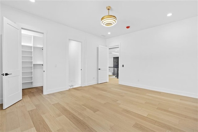 unfurnished bedroom with recessed lighting, baseboards, a spacious closet, and light wood finished floors