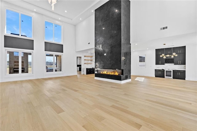 unfurnished living room featuring visible vents, light wood finished floors, and a multi sided fireplace