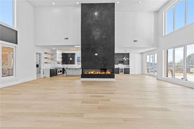 unfurnished living room with recessed lighting, baseboards, a fireplace, and light wood finished floors