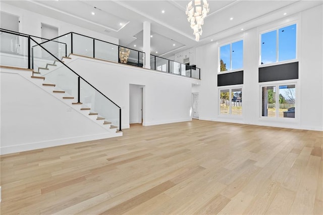 unfurnished living room with recessed lighting, stairway, a chandelier, light wood-type flooring, and baseboards