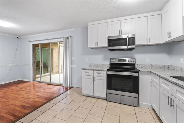 3626 Buford Hwy NE Unit C1, Brookhaven, GA 30329 - kitchen with appliances with stainless steel finishes, white cabinetry, a textured ceiling, light tile patterned floors, and light stone countertops