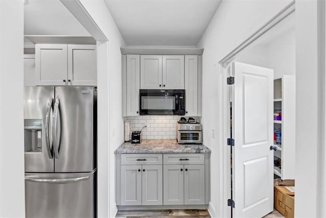 1021 Windsor Creek Dr, Madison, GA 30650 - kitchen with stainless steel fridge, black microwave, tasteful backsplash, light stone countertops, and light wood-style flooring