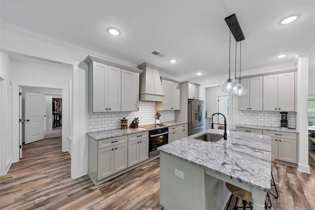 1021 Windsor Creek Dr, Madison, GA 30650 - kitchen with custom range hood, oven, stainless steel fridge, black electric stovetop, and ornamental molding