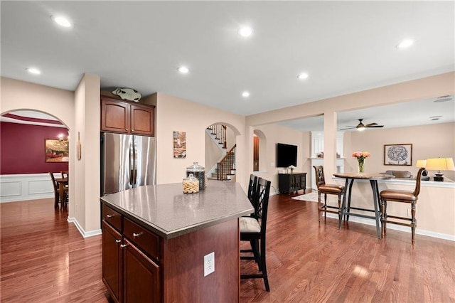 kitchen featuring hardwood / wood-style floors, stainless steel fridge, a breakfast bar, and a kitchen island