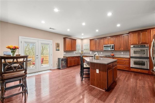 kitchen with a kitchen island, beverage cooler, stainless steel appliances, dark wood-type flooring, and french doors