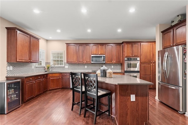 kitchen featuring appliances with stainless steel finishes, sink, wine cooler, a kitchen breakfast bar, and a center island