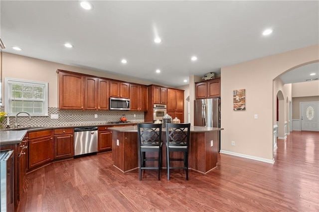 kitchen featuring a breakfast bar, stainless steel appliances, a center island, and sink