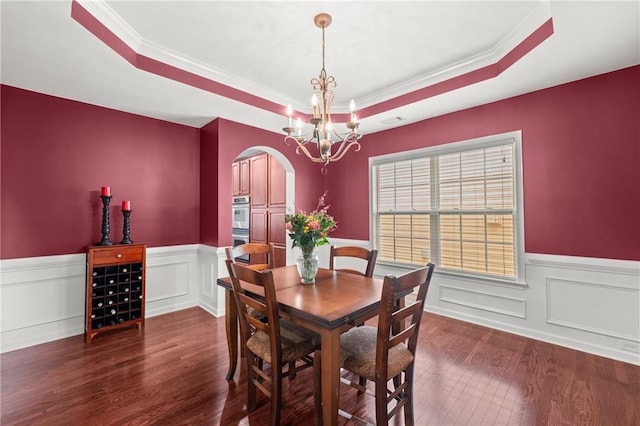 dining area featuring an inviting chandelier, a tray ceiling, ornamental molding, and dark hardwood / wood-style floors