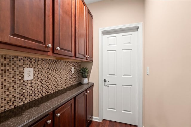 interior space with backsplash, dark hardwood / wood-style flooring, and dark stone countertops