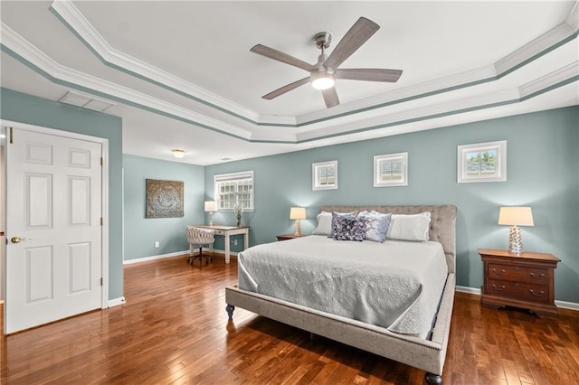 bedroom featuring dark hardwood / wood-style floors, ceiling fan, ornamental molding, and a tray ceiling