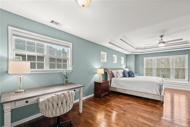 bedroom with dark hardwood / wood-style flooring and a tray ceiling