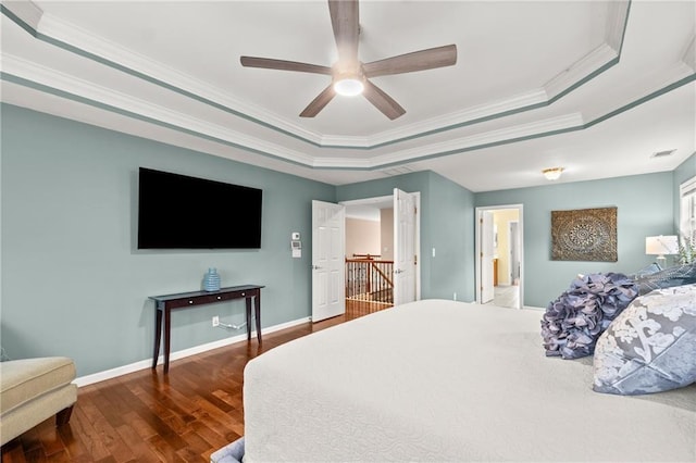 bedroom featuring crown molding, a tray ceiling, dark wood-type flooring, and ceiling fan