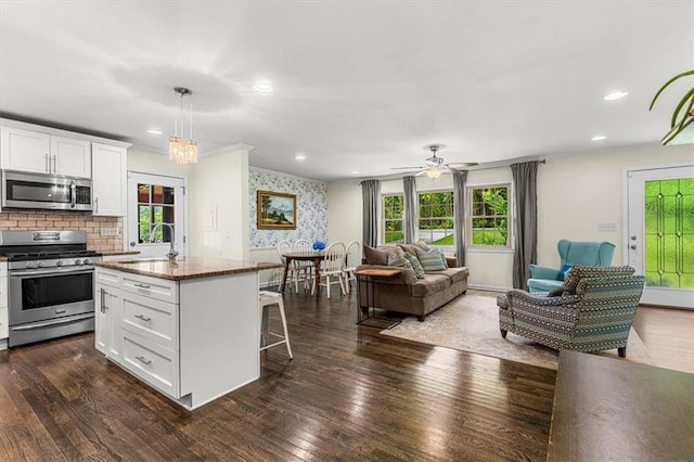 1630 Park Ln, Marietta, GA 30066 - kitchen featuring stainless steel appliances, open floor plan, a breakfast bar, white cabinetry, and a center island with sink