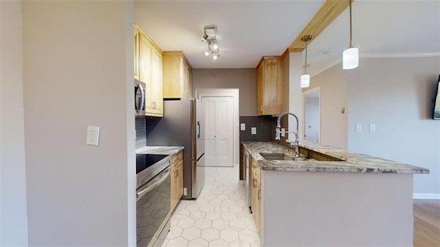 kitchen with kitchen peninsula, appliances with stainless steel finishes, sink, light brown cabinets, and decorative light fixtures