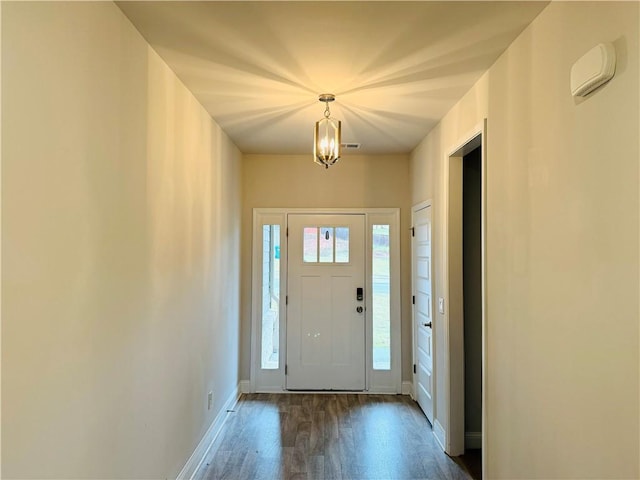 foyer with an inviting chandelier and dark wood-type flooring