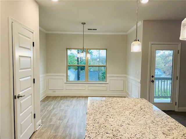 unfurnished dining area featuring a chandelier, hardwood / wood-style flooring, plenty of natural light, and crown molding