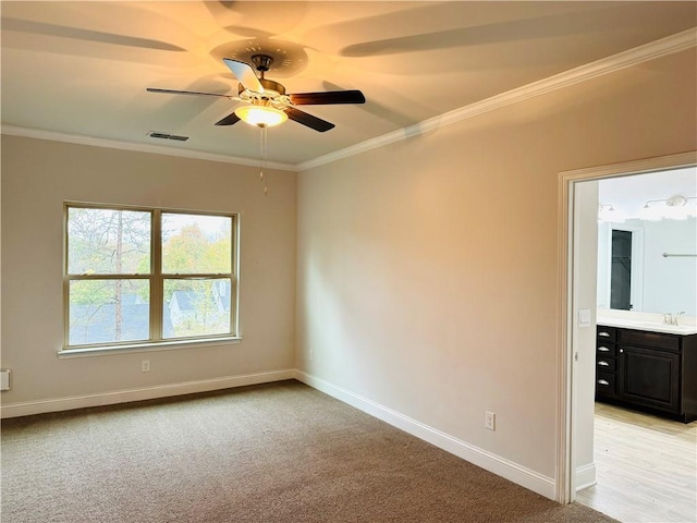 carpeted spare room featuring ceiling fan, sink, and ornamental molding