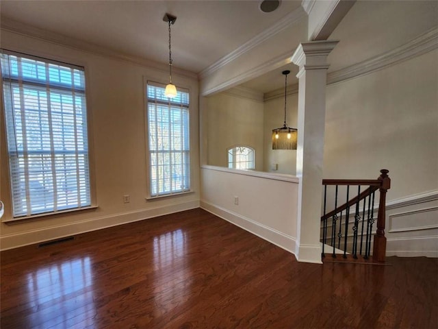 empty room featuring decorative columns, baseboards, visible vents, ornamental molding, and wood finished floors