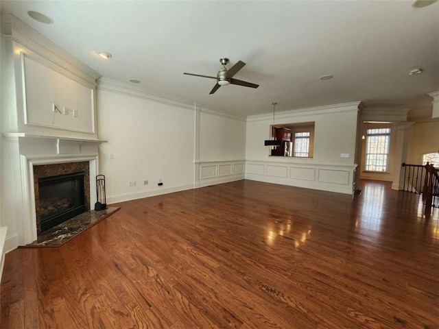 unfurnished living room featuring a high end fireplace, crown molding, and wood finished floors