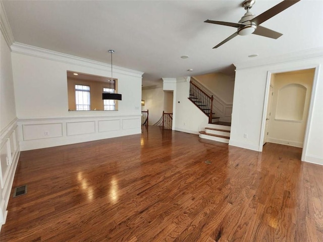 unfurnished living room with ornamental molding, wood finished floors, visible vents, and a decorative wall