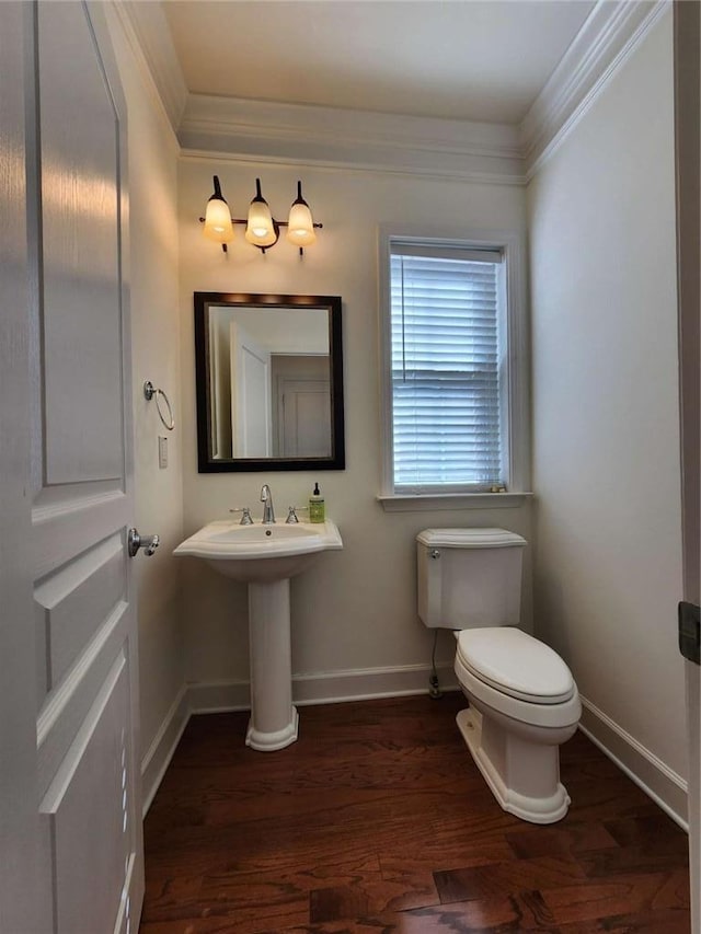 half bath with baseboards, wood finished floors, toilet, and crown molding