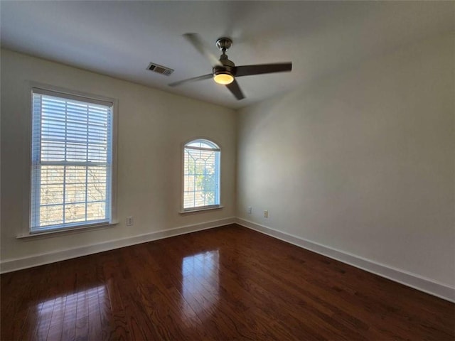 unfurnished room featuring dark wood-type flooring, visible vents, ceiling fan, and baseboards