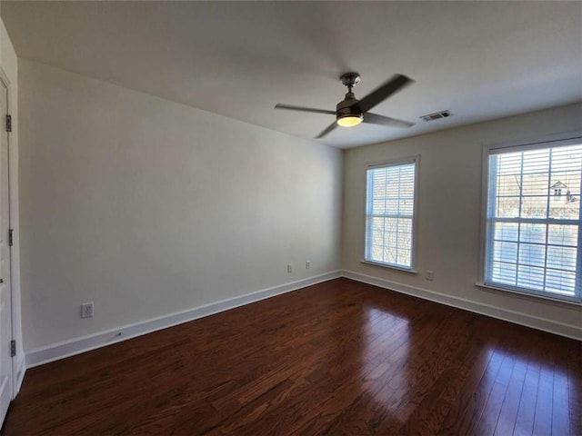 spare room with dark wood-style floors, visible vents, baseboards, and a ceiling fan