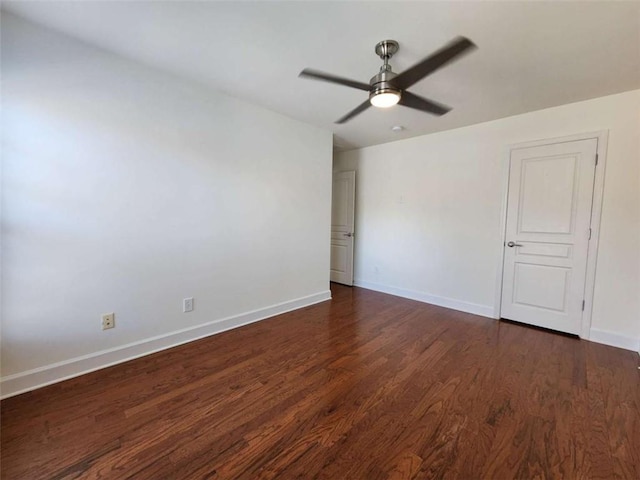 unfurnished room with dark wood-style floors, a ceiling fan, and baseboards